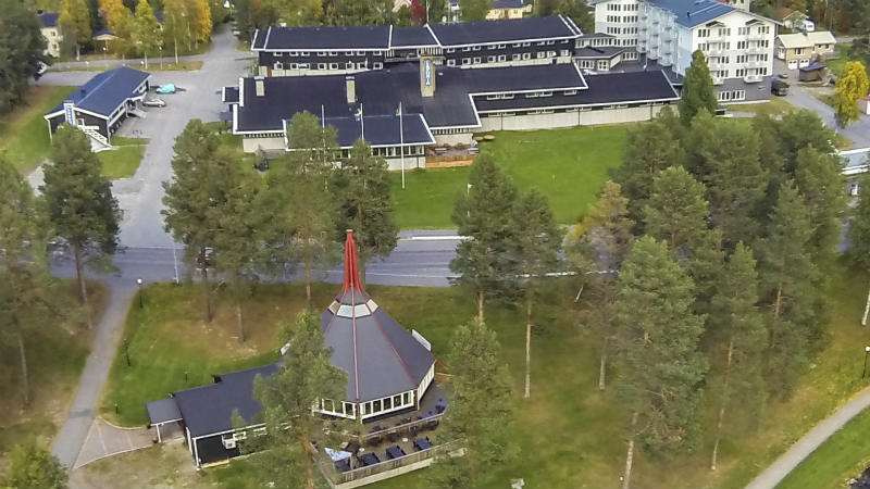 Flygbild över grönskande Hotell Laponia och Laponiakåtan i Arvidsjaur