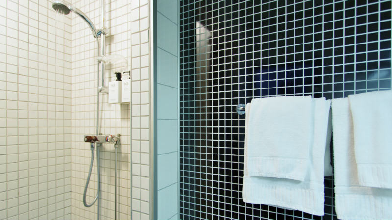 Dusch och handdukar i ett enkelrums WC på Hotell Östersund
